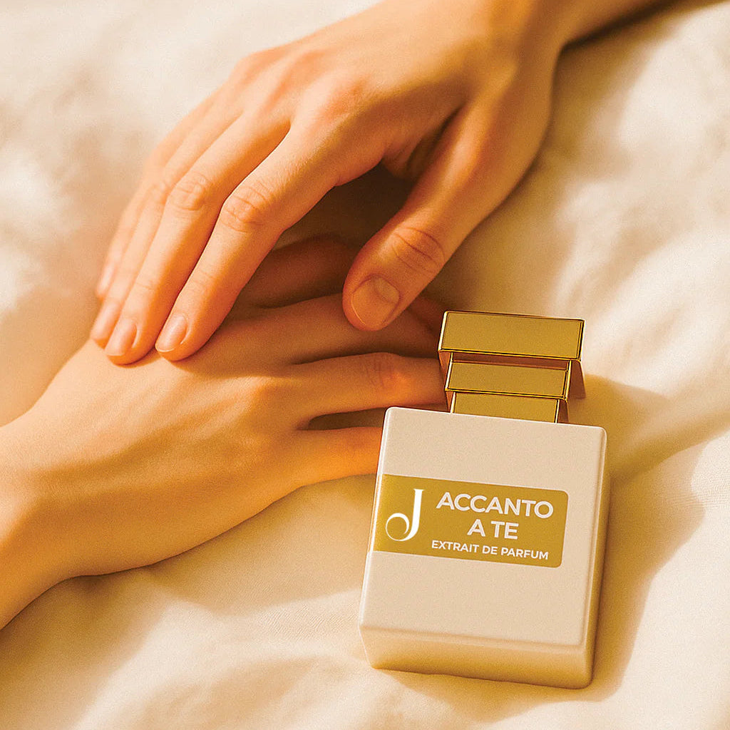 Mani delicate su lenzuola chiare accanto a flacone profumo Accanto a Te oro lusso