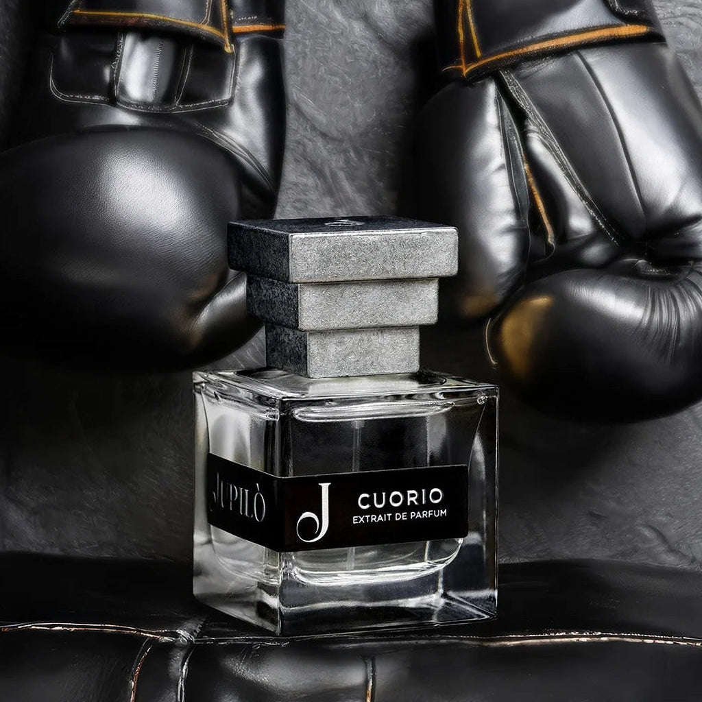 Flacone di profumo Cuorio con guantoni da boxe neri sullo sfondo, atmosfera elegante