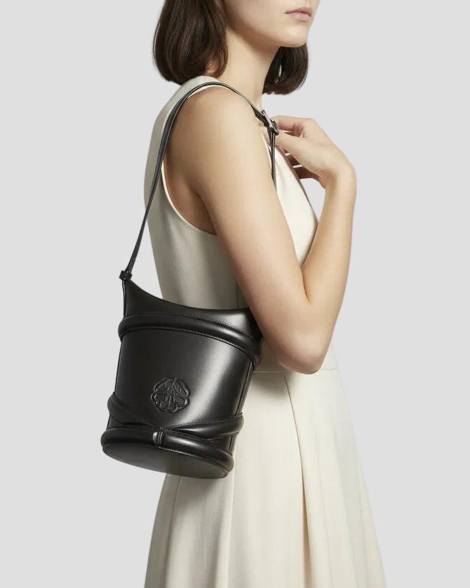 Borsa secchiello in pelle nera elegante indossata da donna con abito chiaro