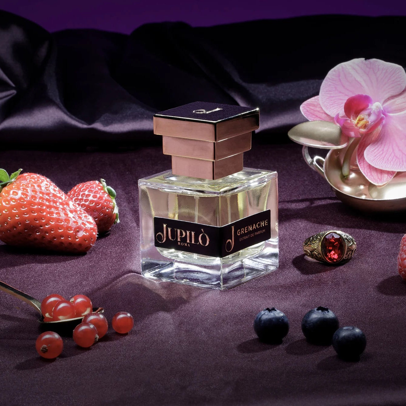 Profumo Jupilò Grenache su seta viola con fragole, mirtilli, ribes rosso e orchidea rosa