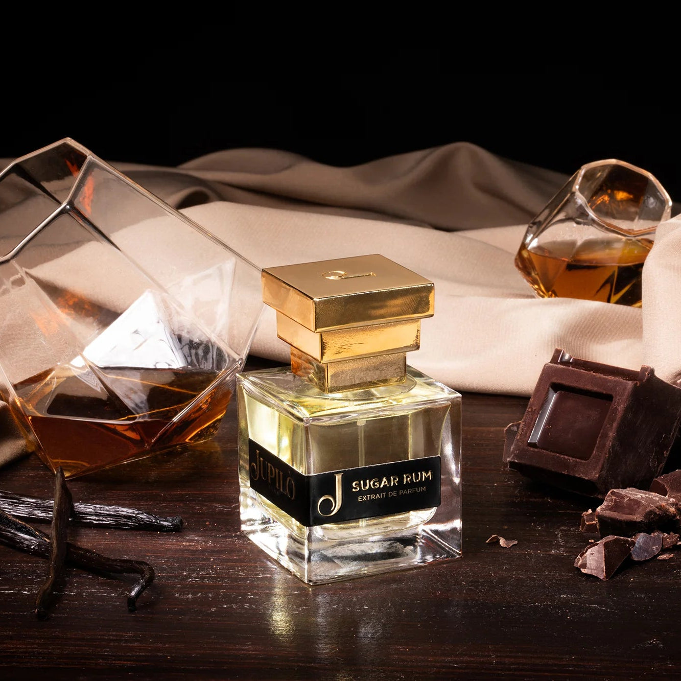 Flacone di profumo Sugar Rum con tappo dorato, bicchieri di rum, cioccolato fondente e vaniglia.