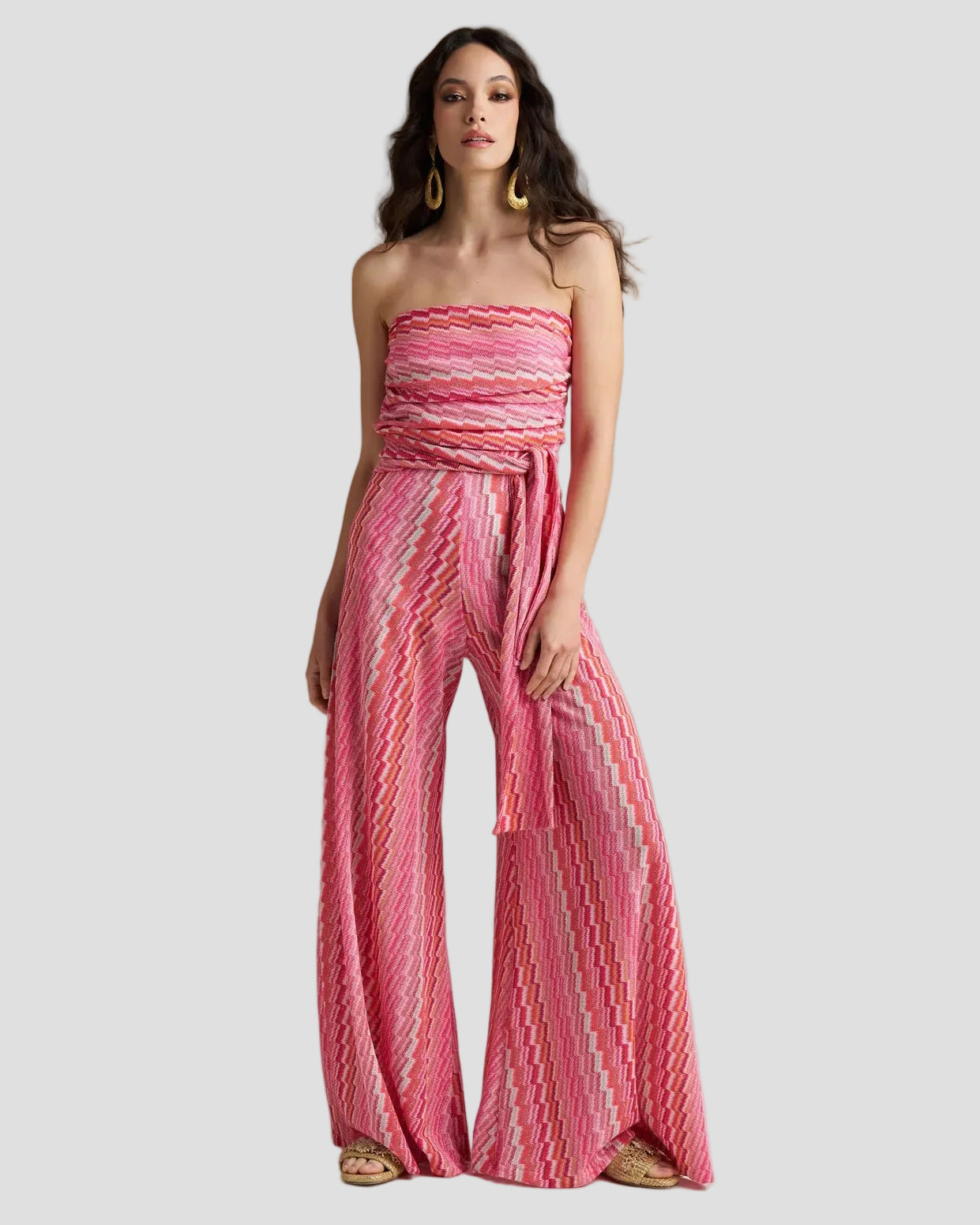 Look estivo con Jumpsuit Rachel electric fuxia a fantasia chevron. Tuta senza spalline con cintura in vita e pantaloni ampi, abbinata a grandi orecchini d'oro e sandali gioiello.
