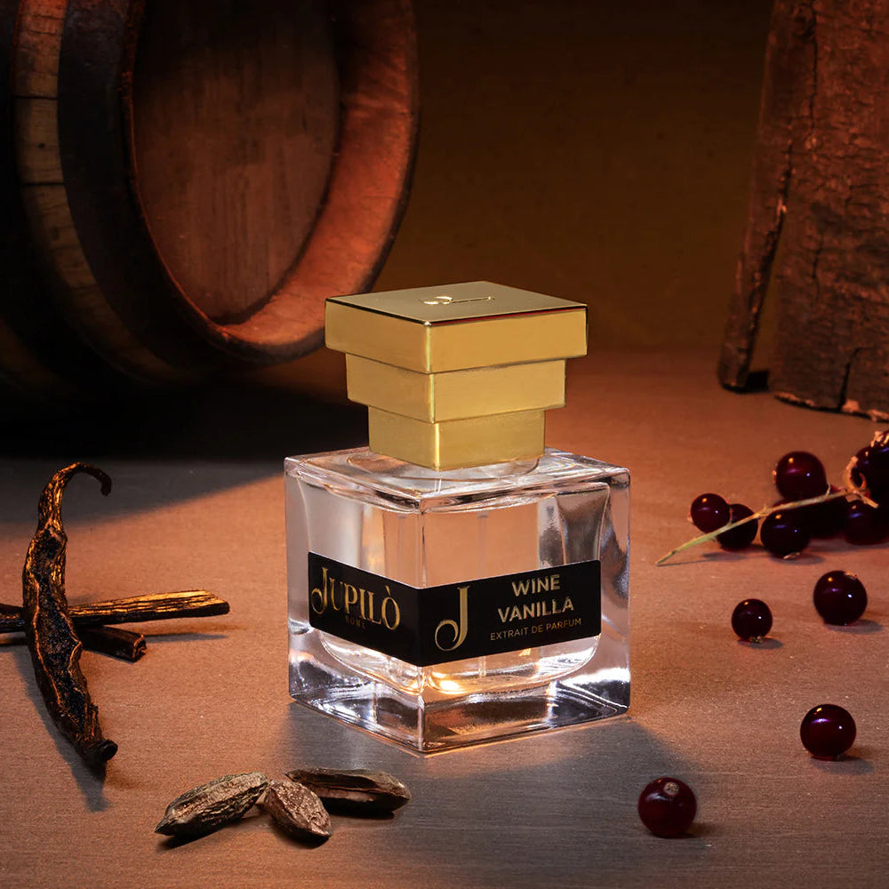 Flacone di profumo Wine Vanilla con tappo dorato, circondato da bacche rosse e vaniglia.
