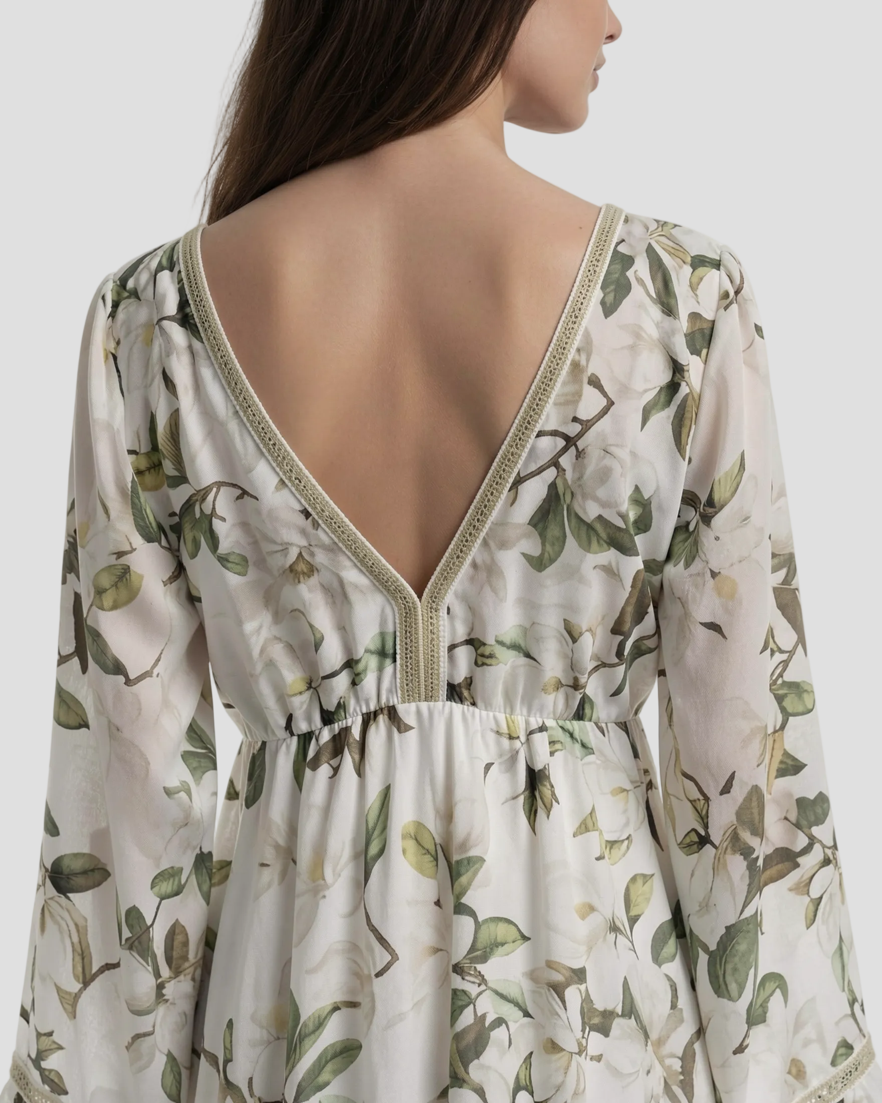 modella di spalle indossa Abito lungo Pho Firenze in cotone e seta, fantasia floreale verde e bianca con nappine e taglio sottoseno.