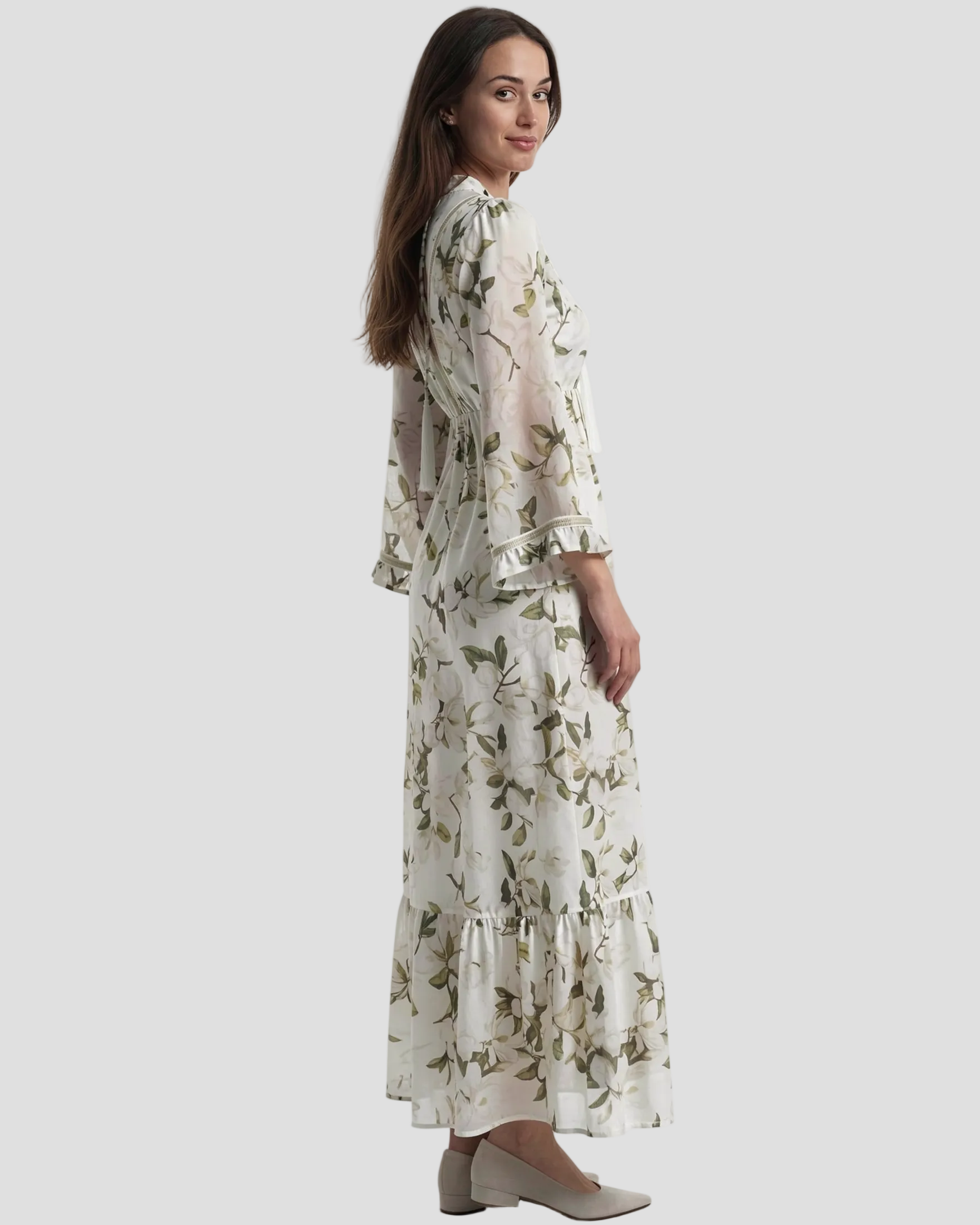Modella indossa di lato Abito lungo Pho Firenze in cotone e seta, fantasia floreale verde e bianca con nappine e taglio sottoseno.