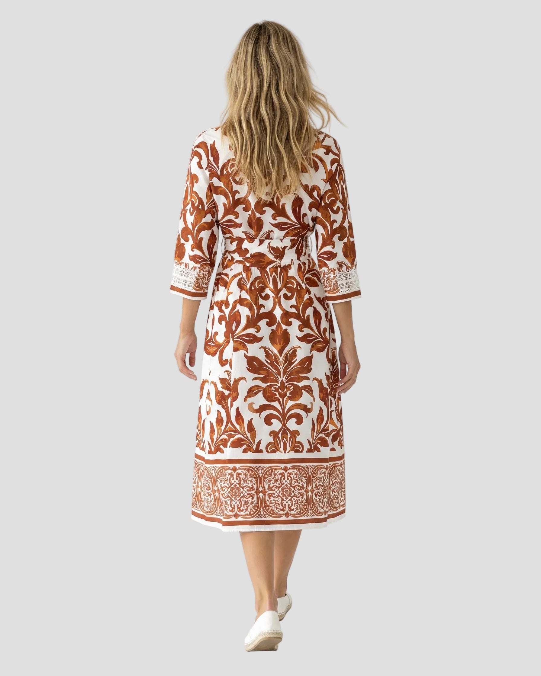 Vista posteriore della modella che cammina indossando l'abito midi Milva MI, mostrando il fit fluido e il pattern damascato sulla schiena e sulla gonna.