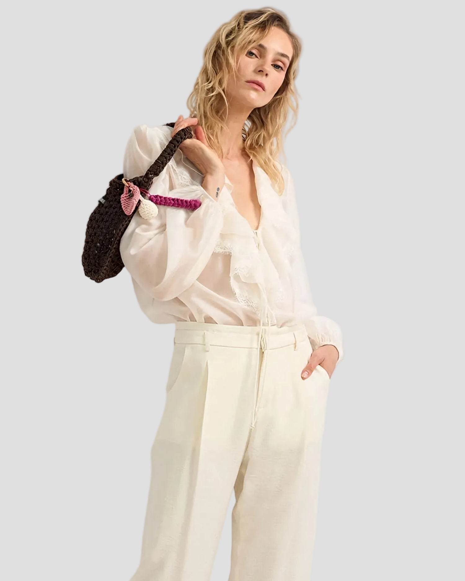 Modella con blusa semi trasparente color avorio con volant e pantaloni chiari su sfondo drappeggiato bianco-91