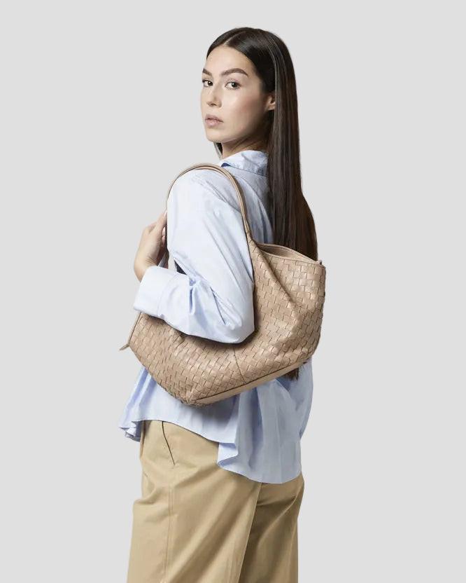 Modella con borsa intrecciata in pelle beige a spalla, stile elegante e artigianale.