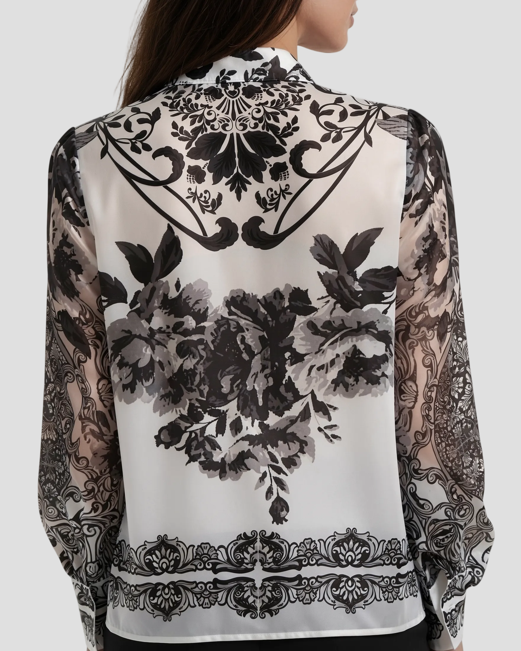 Dettaglio posteriore della camicia con focus sulla stampa ornamentale simmetrica sulle spalle e sul design armonioso dei fregi neri su fondo bianco.