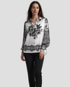 Vista frontale di una camicia elegante da donna in bianco e nero con stampa floreale centrale e motivi barocchi su maniche e bordo inferiore.