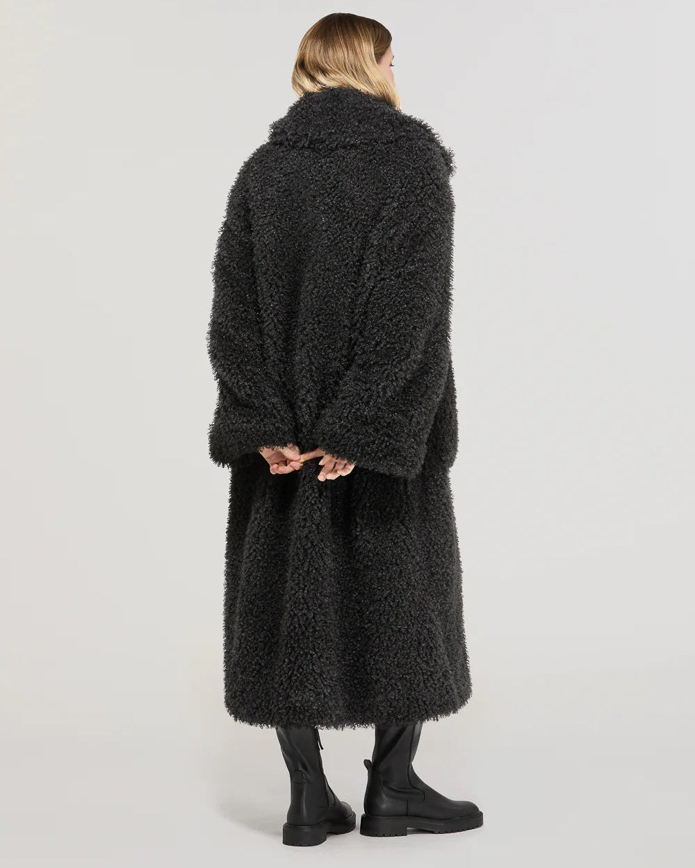 Cappotto oversize lungo donna nero in pelliccia eco, modello di schiena, stivali neri