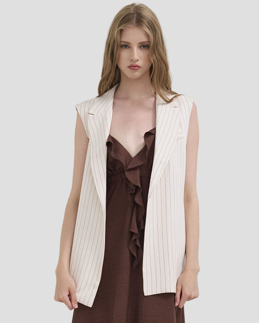 Gilet donna gessato color burro senza maniche su abito marrone, moda elegante.
