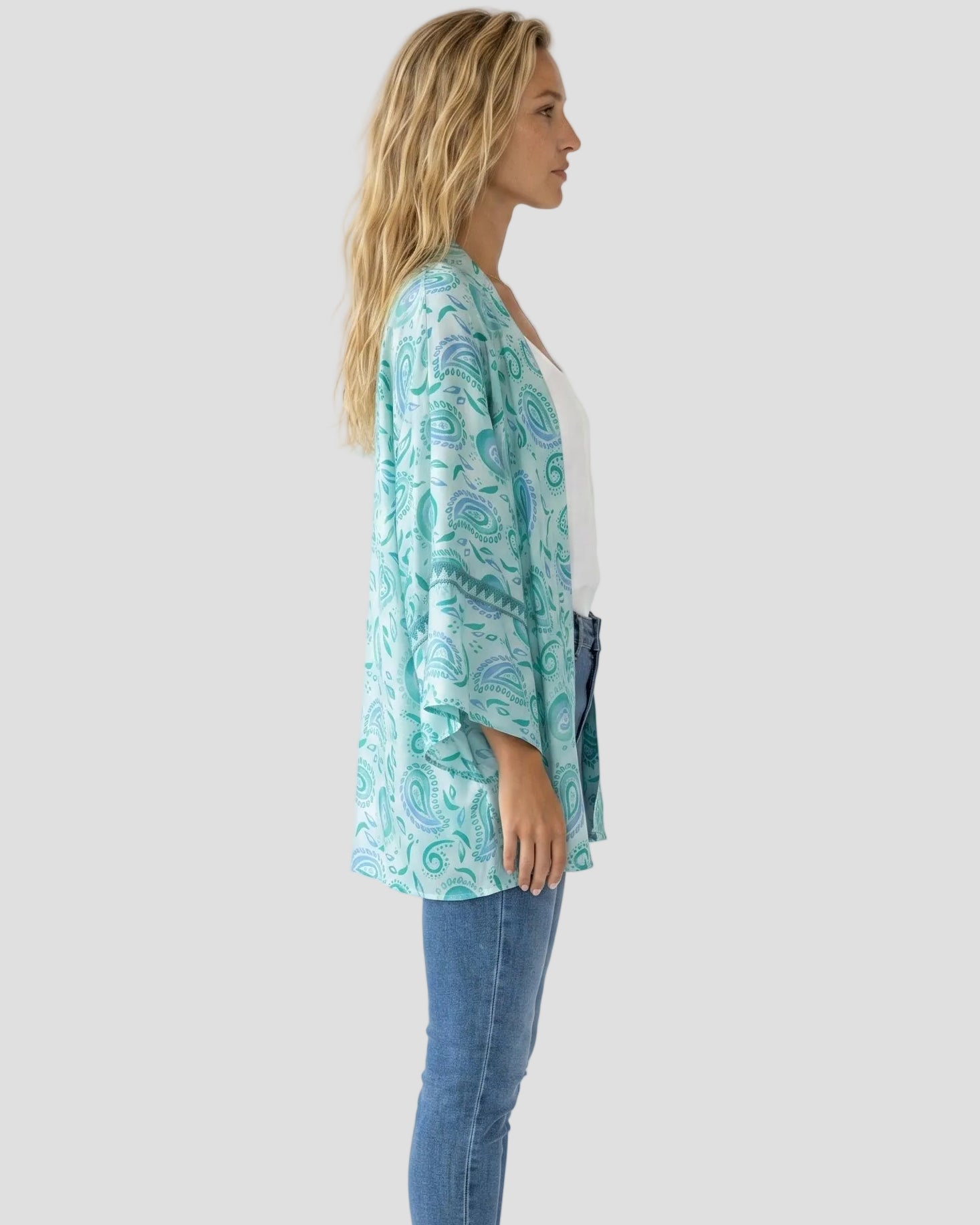 Profilo laterale del kimono azzurro e verde acqua Pho Firenze con jeans e top bianco"
