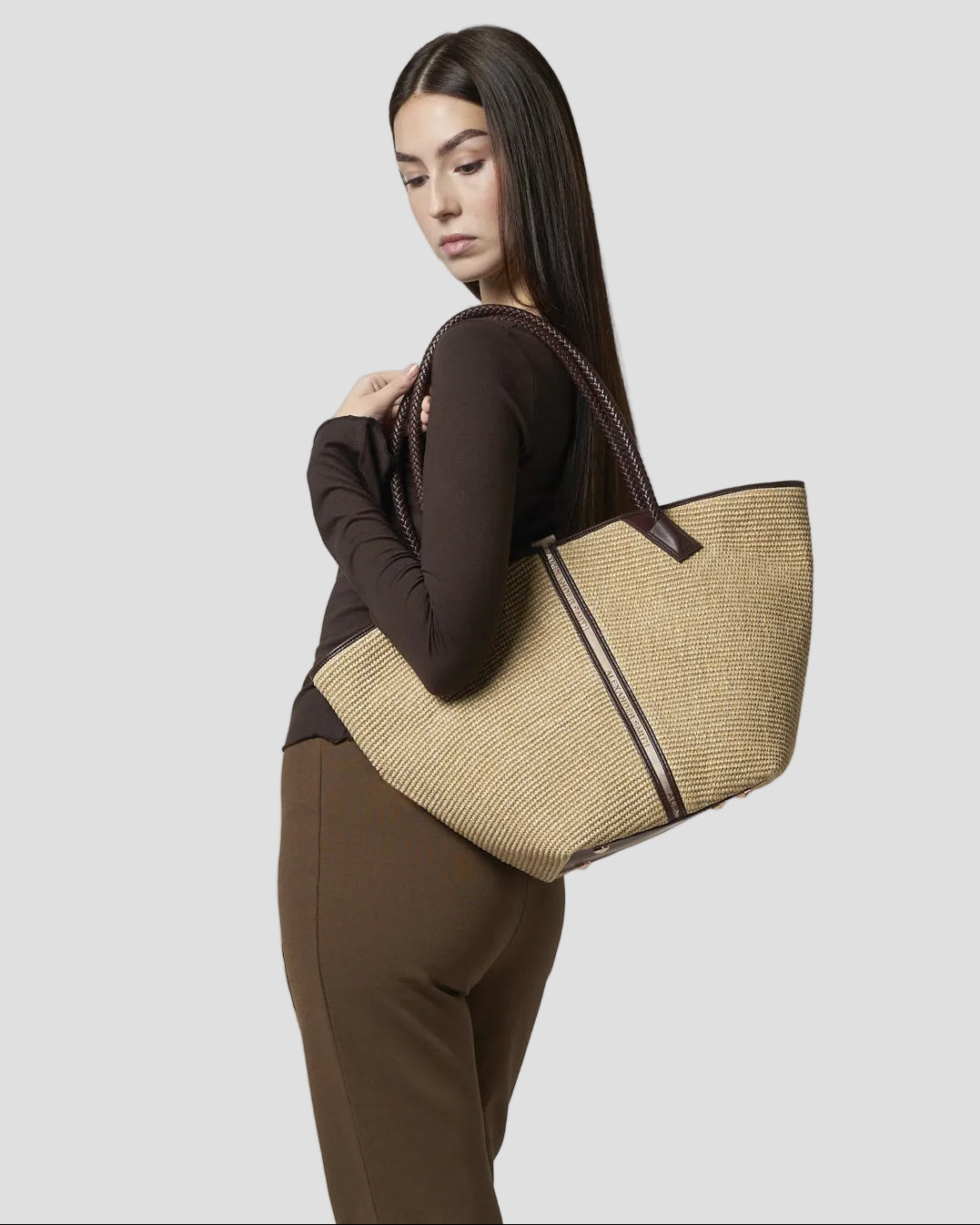 Modella indossa Borsa a spalla in rafia beige con manico intrecciato in pelle marrone