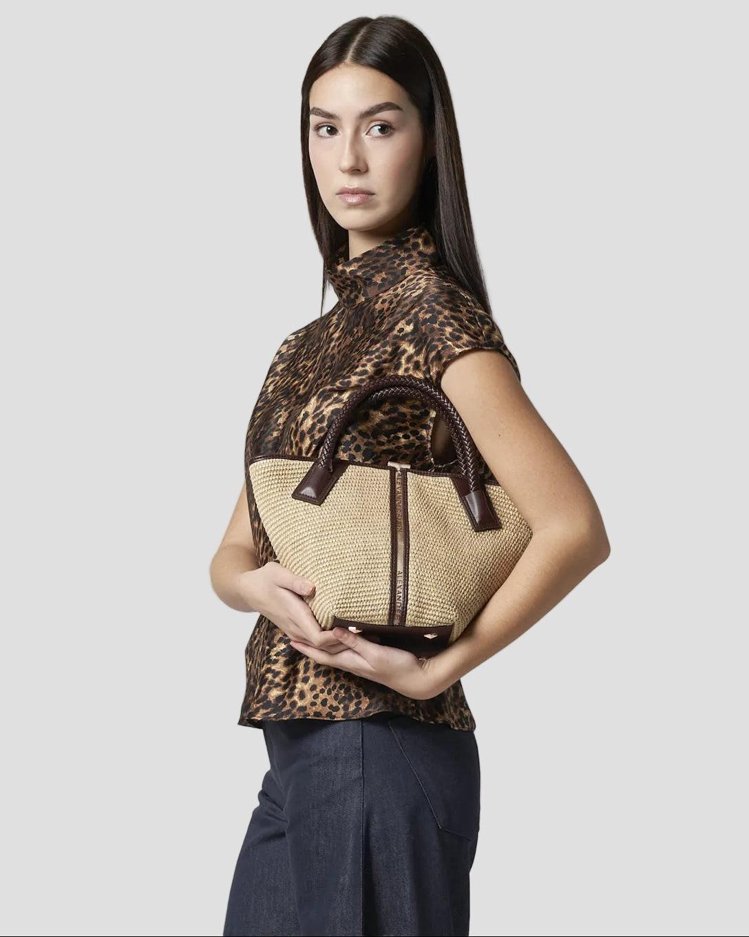 Donna con borsa a mano in rafia e manico intrecciato in pelle marrone, moda elegante