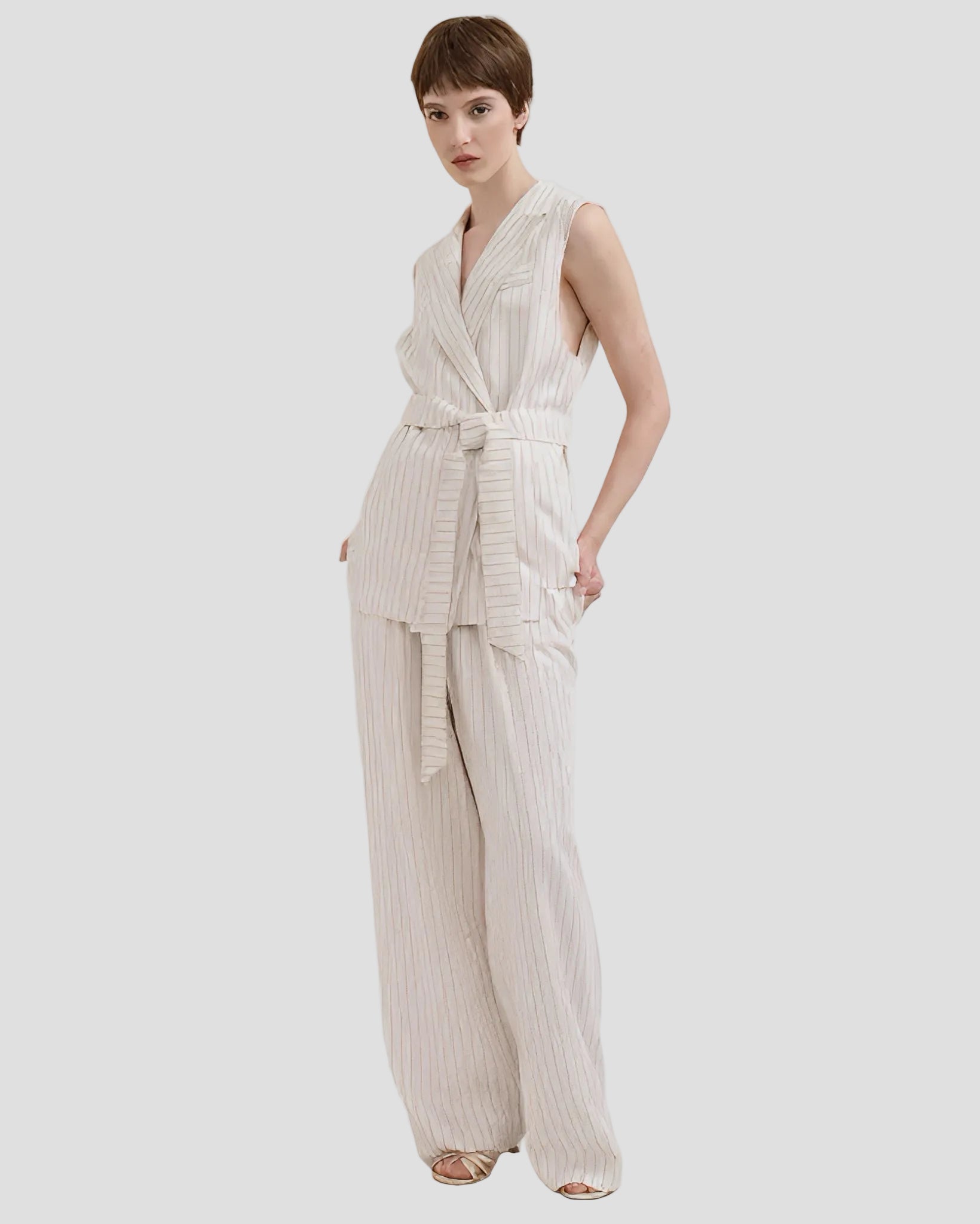 Completo elegante donna con pantaloni gessati burro e gilet smanicato, stile alta moda.