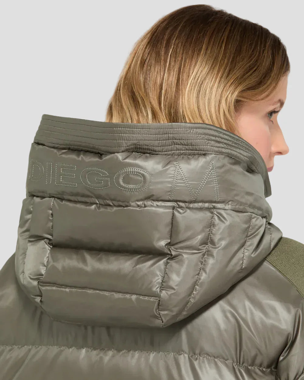 Piumino verde scuro da donna con cappuccio, tessuto lucido e dettaglio trapuntato.