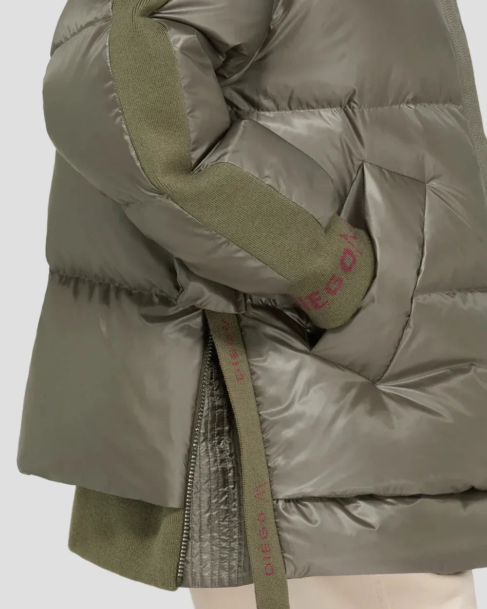 Dettaglio piumino verde scuro da donna, tessuto lucido, inserti in maglia, zip laterale.