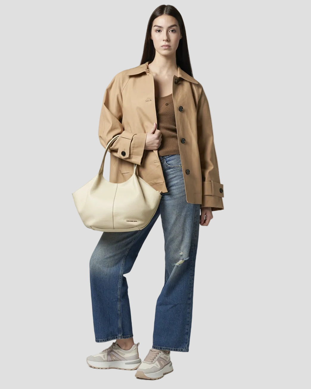 modella in piedi indossa al braccio una borsa rachel medium alexander smith in  pelle bottalata color avorio