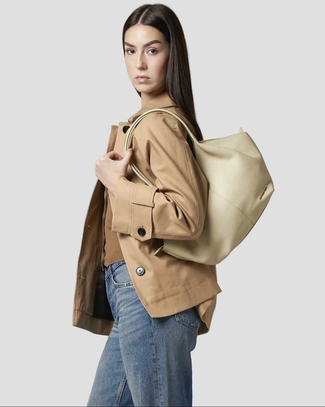 Modella in piedi indossa a spalla la borsa Rachel Medium di Alexander Smith, in pelle bottalata color avorio